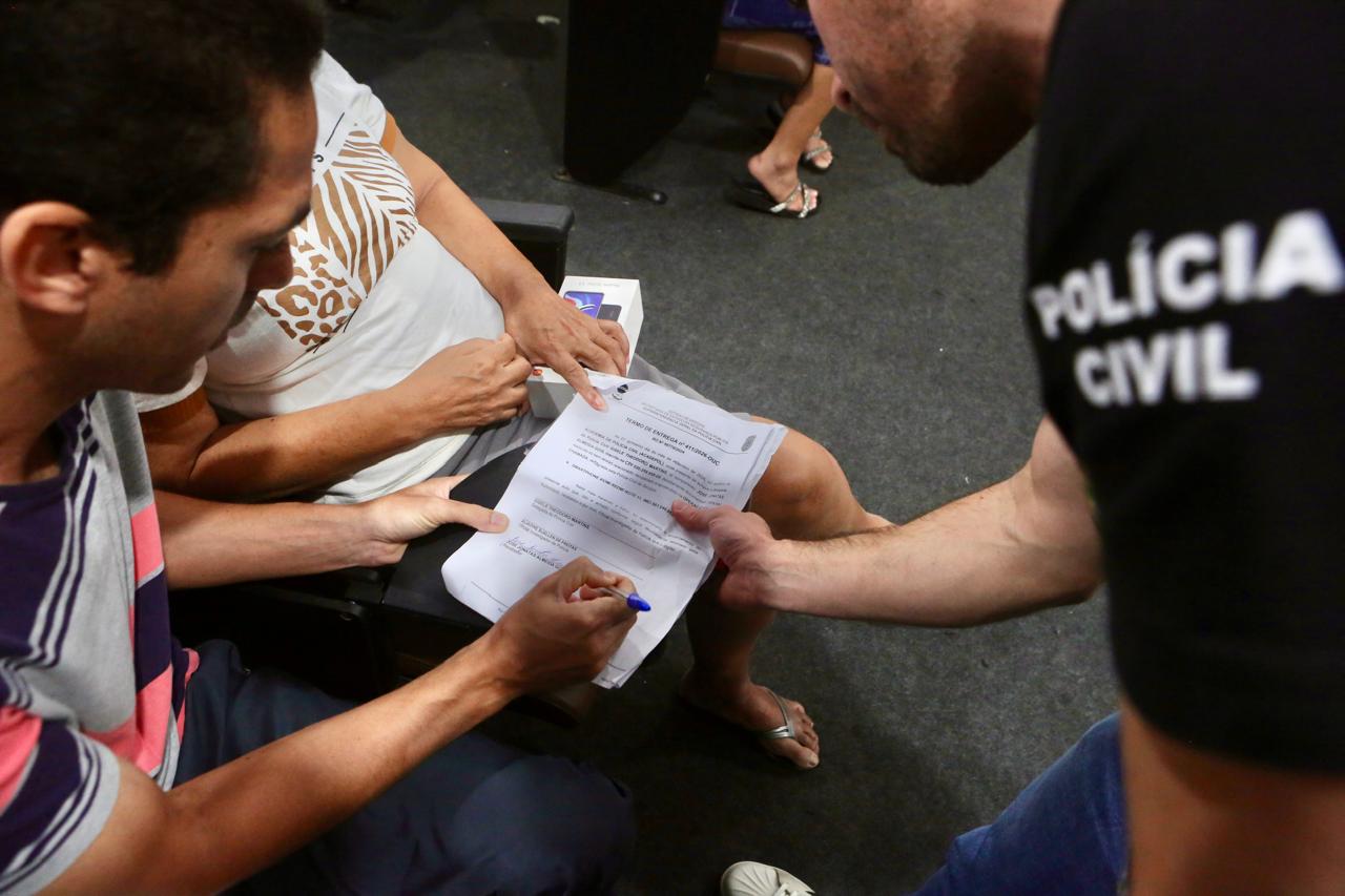 Proprietário assina o termo de entrega do aparelho recuperado pela Polícia Civil